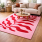 Living room with a pink rug featuring red leaf patterns, a beige sofa, and a wooden coffee table.