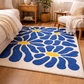 Blue floral rug with yellow centers on a wooden floor in a living room setting.