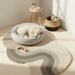 Dog resting on a modern pet bed in a bright room with a rug and small table.