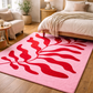 Pink rug with red abstract design in a bedroom setting