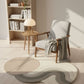 Modern living room with a wavy patterned rug, armchair, and bookshelf.