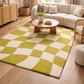 Living room with a green and white checkered rug, beige sectional sofa, and wooden coffee table.
