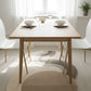 Dining table set with chairs in a bright room with large windows.