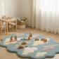 Children's play area with a blue rug featuring cloud designs, wooden toys, and a small table.