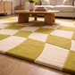 Living room with a checkered green and beige rug, wooden coffee table, and beige sofa.