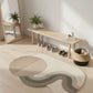 Modern interior with a round rug, wooden bench, and potted plants.