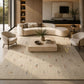 Close-up of a textured area rug with a cream-colored base, featuring a central rust-brown abstract symbol and scattered blue and gray motifs.