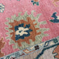 Close-up of a patterned rug with pink background and multicolored design