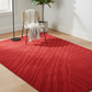 Red patterned rug on a wooden floor with a chair and plant in the background