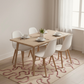 Dining room with wooden table and white chairs on a patterned rug.