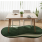 Dining table set with chairs on a wooden floor, featuring a green and white rug.