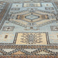 Close-up of a patterned rug with geometric designs in blue, beige, and brown.