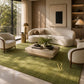 An olive green textured area rug with a small gold monogram logo in the lower right corner, displayed flat against a white background.