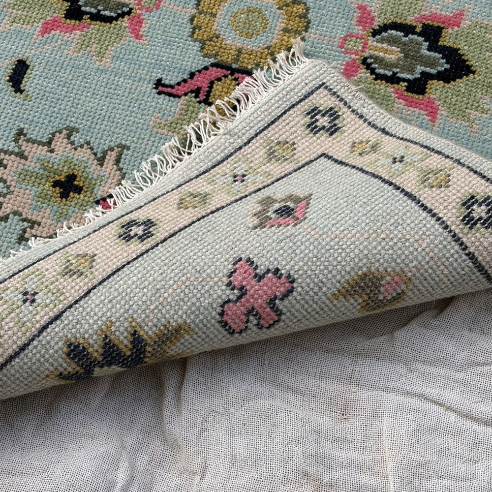 Close-up of a patterned rug with floral designs on a textured surface.