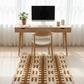 Home office setup with a wooden desk, chair, computer monitor, and decorative rug.