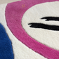 Close-up of a colorful rug with geometric patterns and a brand logo.