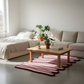Modern living room with a pink rug, wooden coffee table, and beige sofa.