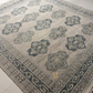 Close-up of a patterned rug with geometric designs on a tiled floor.