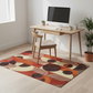 Modern home office with a wooden desk, chairs, and a colorful area rug.