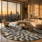 A modern living room with a large round area rug featuring an abstract wavy pattern in slate blue and cream. The room is styled with a curved cream boucle sofa, a low round wooden coffee table, and a matching accent chair, all set against a warm sunset backdrop with a city skyline visible through floor-to-ceiling windows.