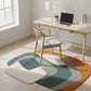 Modern home office with a colorful rug, desk, chair, and laptop.