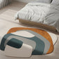Abstract patterned rug on a wooden floor in a bedroom setting