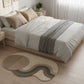 Bedroom with a bed, decorative pillows, and a rug on a wooden floor.