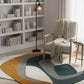 Modern living room with a colorful rug, bookshelf, and armchair.