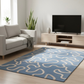 Modern living room with a blue patterned rug, gray sofa, and TV stand.