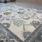 Close-up of a patterned rug with floral designs on a light-colored floor.