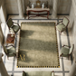 Grand room with a large rectangular rug featuring a gold letter 'R', flanked by ornate chairs and a wooden table.
