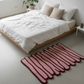 Pink and red striped rug on a light gray floor in a bedroom setting.