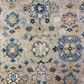 Close-up of a patterned rug with floral and geometric designs in blue, beige, and brown.