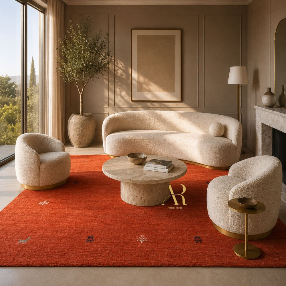 A styled interior scene with a cream curved sofa, two matching boucle armchairs, a round stone coffee table, and a large rust-red area rug. The room has warm neutral walls, wood paneling, a window with outdoor view, and decorative plants and lamps.