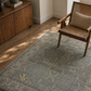Living room with a patterned rug, wooden chair, and sideboard.