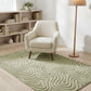 Beige armchair on a green patterned rug in a room with a bookshelf and lamp.