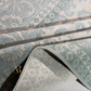 Close-up of a patterned fabric with a brand logo in the corner.