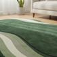 Green and beige patterned rug in a living room setting with a couch and plant.