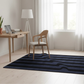 Navy blue rug with wavy pattern in a room with a desk and chair.