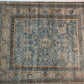 Decorative rug with intricate patterns in blue, beige, and brown on a plain background