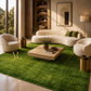 A rectangular green artificial turf or grass mat with a textured grass-like surface, laid out on a light-colored tiled floor. A gold monogram logo reading 'AR' is printed near one corner.