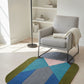 Geometric patterned rug in a modern living room with a gray armchair.