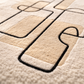 Close-up of a textured rug with geometric patterns in beige and black.