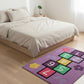 Colorful children's rug with numbers and letters on a wooden floor in a bedroom.