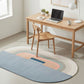 Modern home office with a wooden desk, chair, and colorful rug.