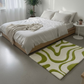 Bedroom with a green and white patterned rug on the floor.