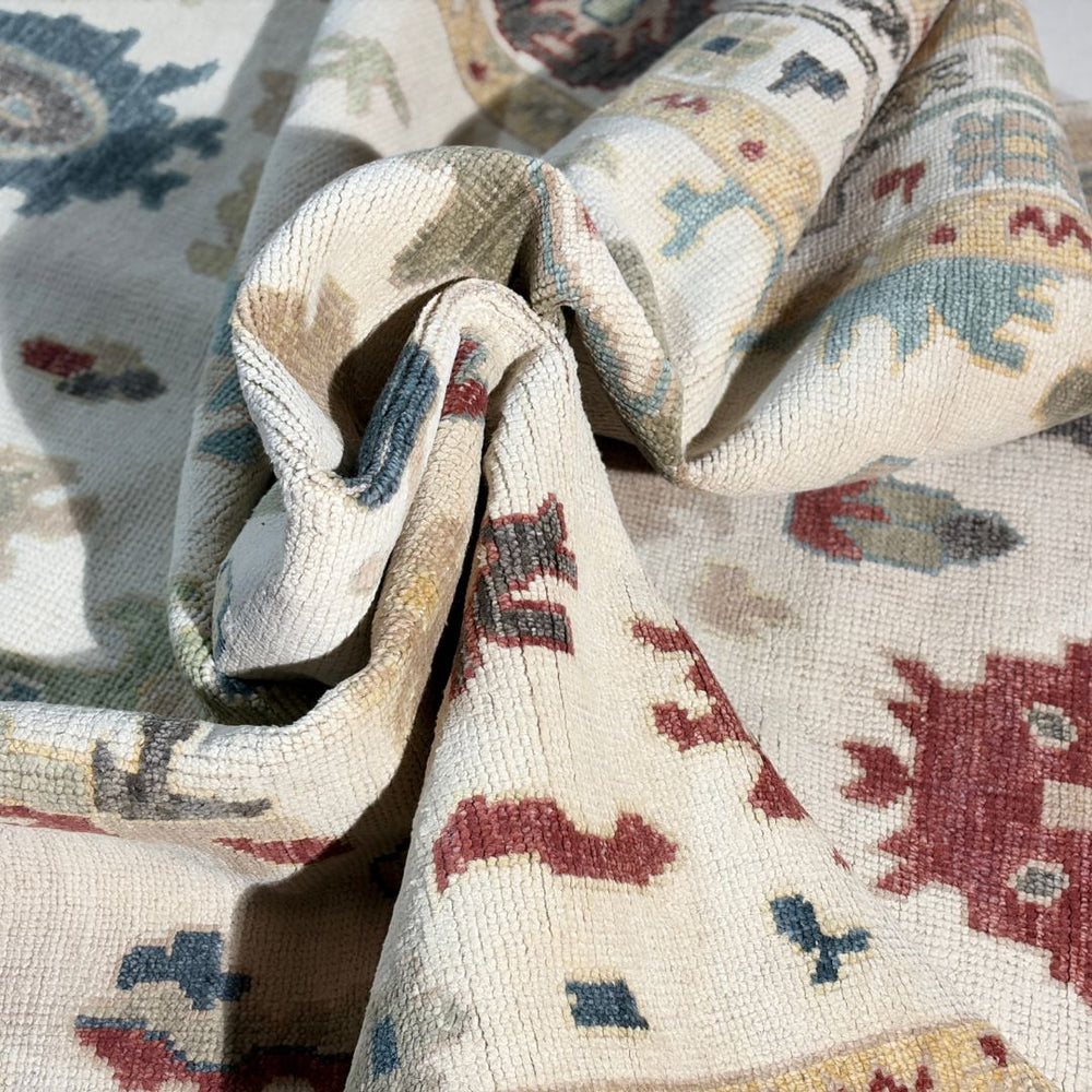 Close-up of a patterned fabric with geometric designs in red, blue, and beige.
