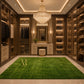 A rectangular green artificial turf or grass mat with a textured grass-like surface, laid out on a light-colored tiled floor. A gold monogram logo reading 'AR' is printed near one corner.