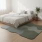 Bedroom with a bed and green wavy rug on wooden floor
