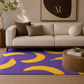 A purple area rug with a bold yellow banana pattern, styled in a modern living room setting under a cream-colored sofa.